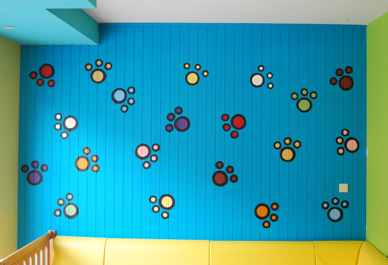 decoratieve beschildering van een muur in een kinderdagverblijf met gekleurde pootjes