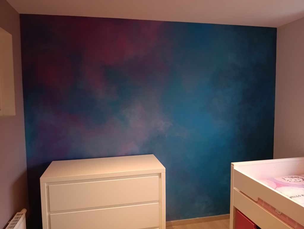 muur in kinderkamer geschilderd met decoratieve schildertechniek in blauwe en fuchsia tinten