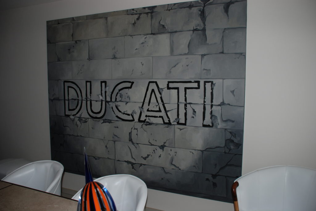 schilderij met het logo van Ducati op bakstenen in een kantoor