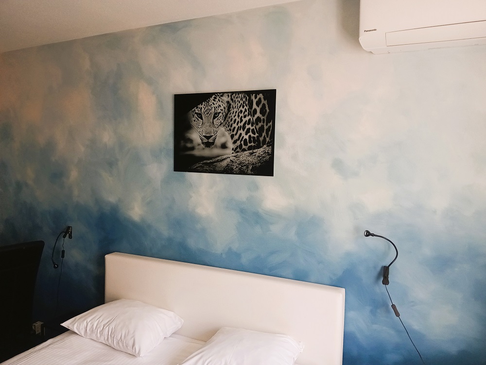 geschilderde accentmuur in een hotelkamer met blauwe tinten